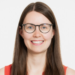 Junge Frau mit Brille und dunklem Oberteil, freundlich blickend.